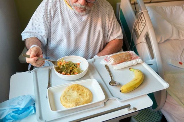 Senior patient eating healthy meal in hospital bed